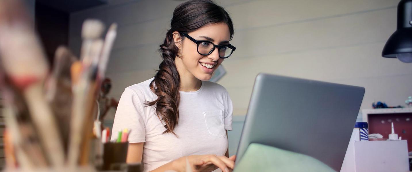 Eine fröhliche junge Frau bedient einen Laptop