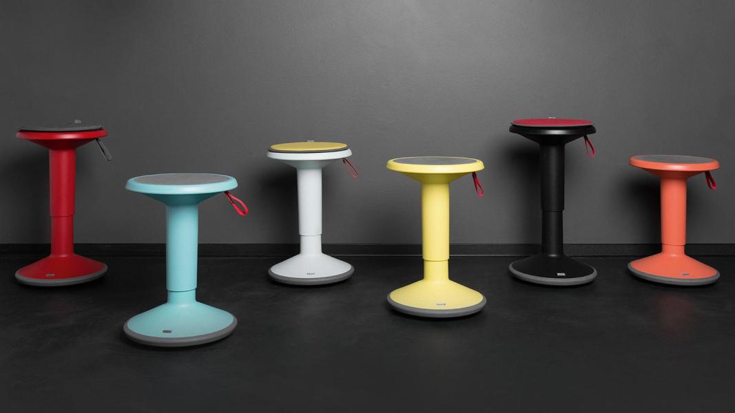 Hocker Upis1 - Eine Reihe bunter Hocker in verschiedenen Farben, ordentlich nebeneinander aufgestellt.